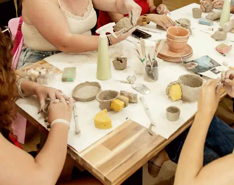 Mãos a moldar barro num atelier de cerâmica.